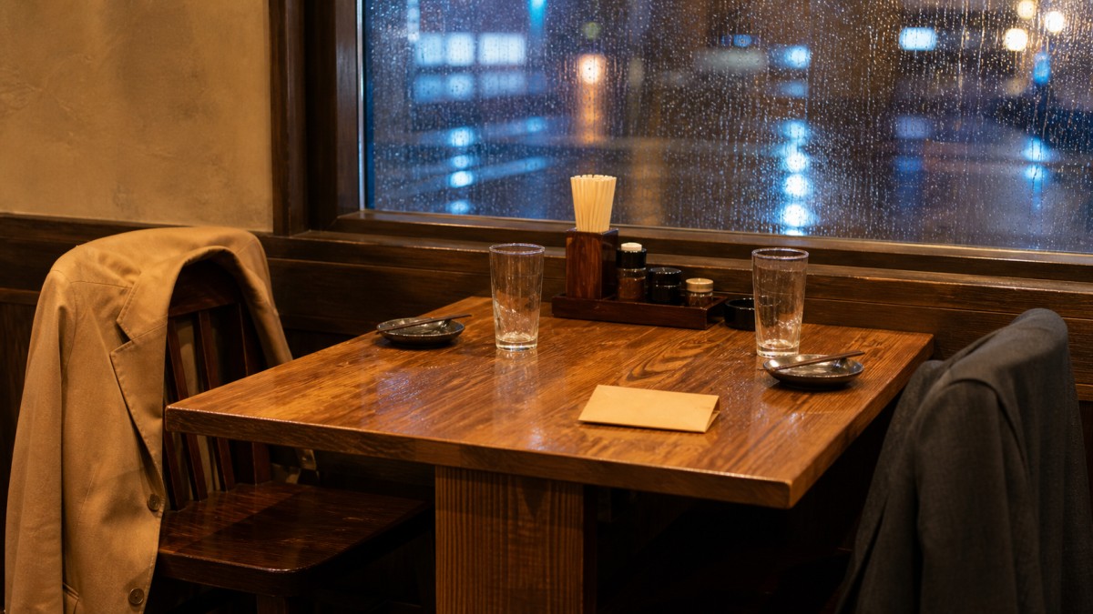 雨の夜に二人分のグラスが残る居酒屋の席